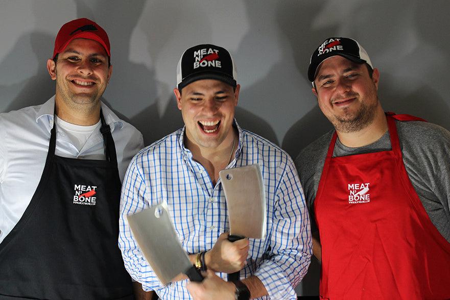 Cheerful butchers holding cleavers, promoting Meat N Bone brand.